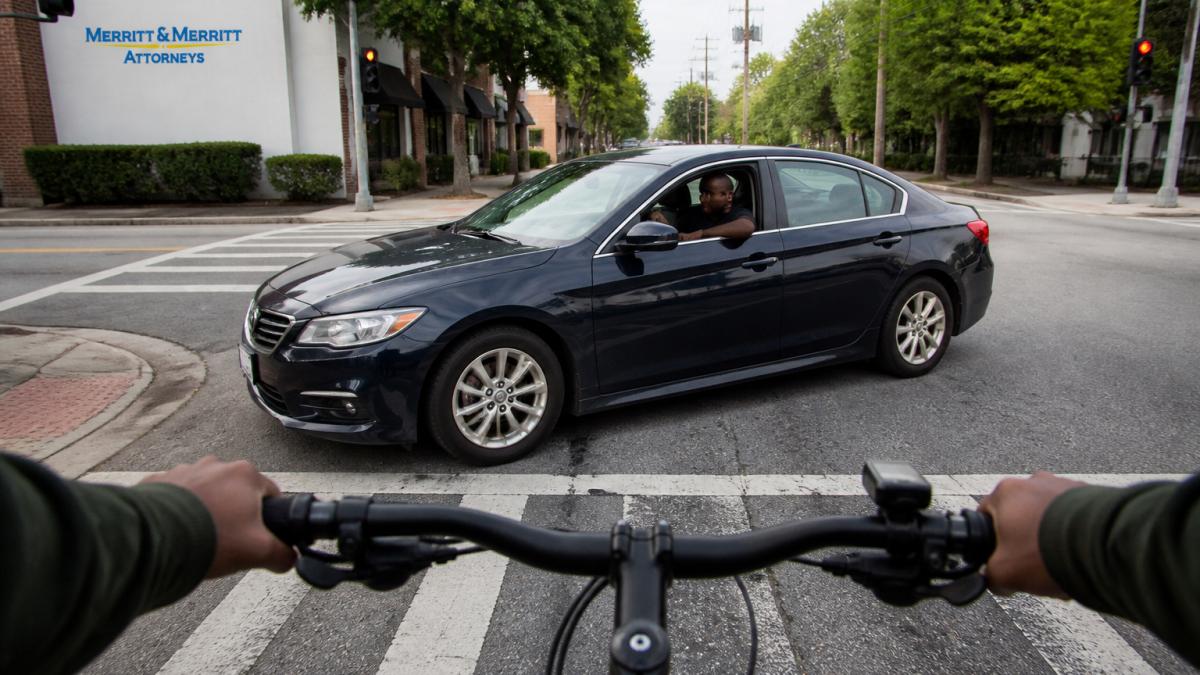 A distracted driver approaching a cyclist at a busy intersection where bicycle accidents often occur.